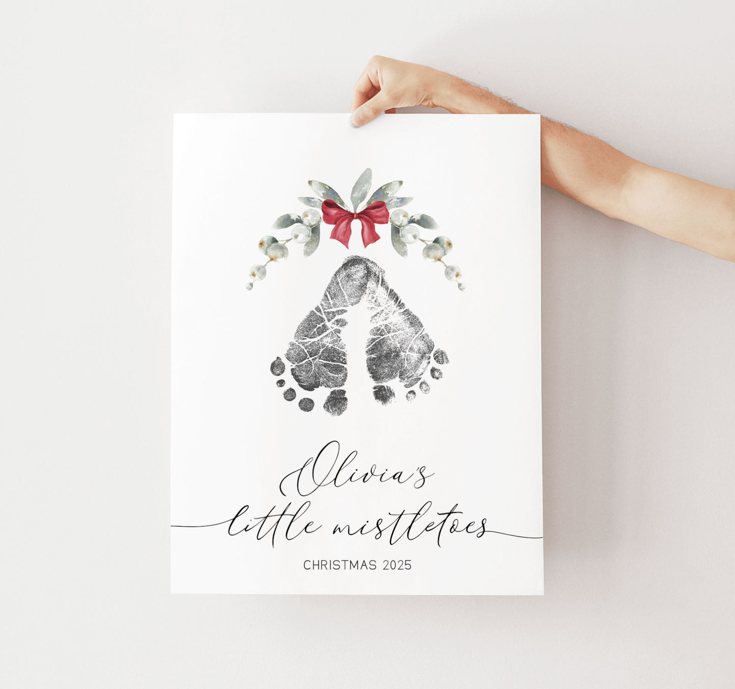 Print with footprints mistletoe, and a bow held by a hand on a white background
