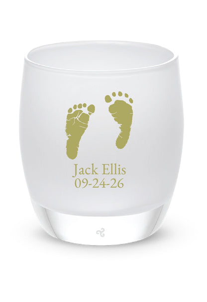White tea candle holder with gold footprints and text on a white background, featuring the Glassybaby brand.