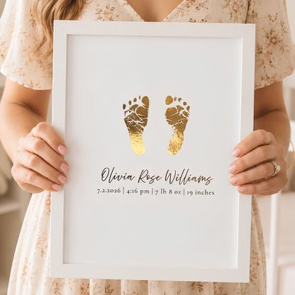 A person holding a white framed personalized baby keepsake print featuring gold foil baby footprints and custom text with the name 'Olivia Rose Williams' and birth details.