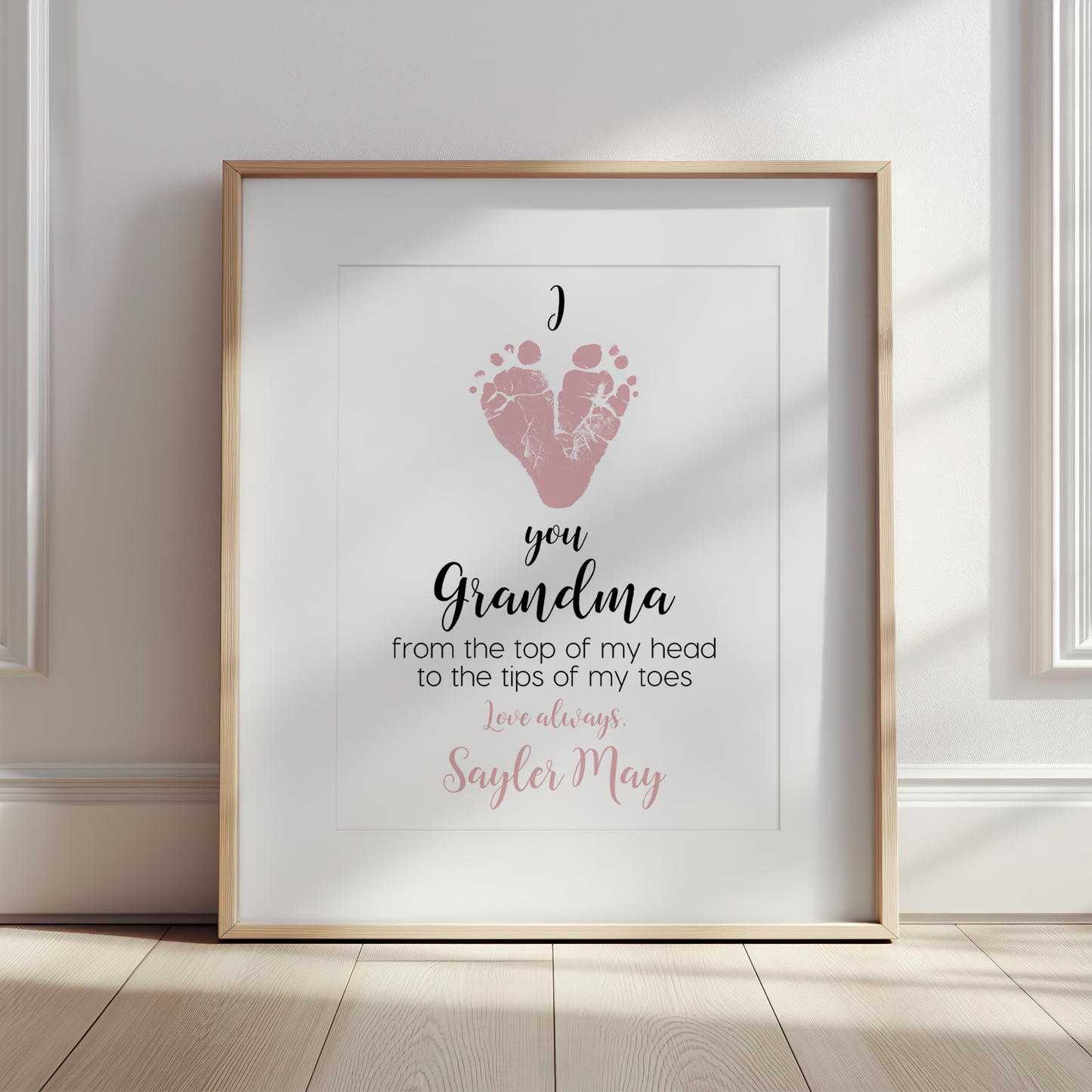 Framed print with pink footprints and text on a white wall.