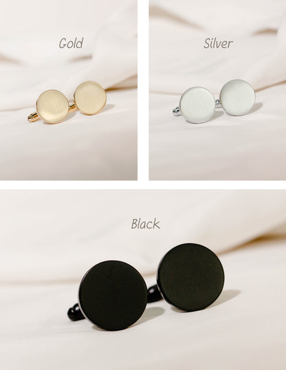 Three pairs of round stud earrings shown on a soft cream fabric background, labeled Gold, Silver, and Black. Each pair has a flat circular face with a post and backing visible. These are for baby footprint keepsake cufflinks.