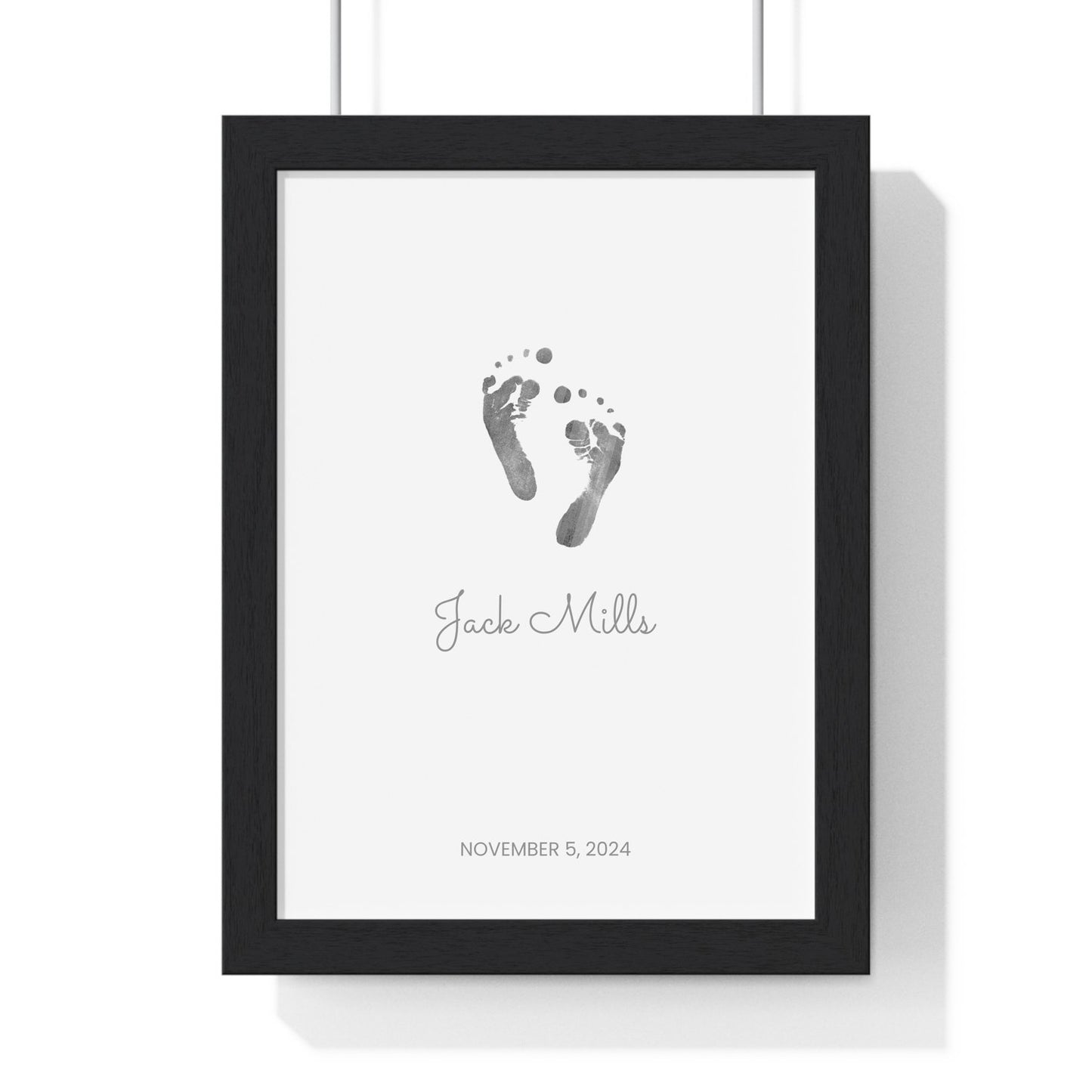Framed keepsake print with baby footprints on a white background with black frame.