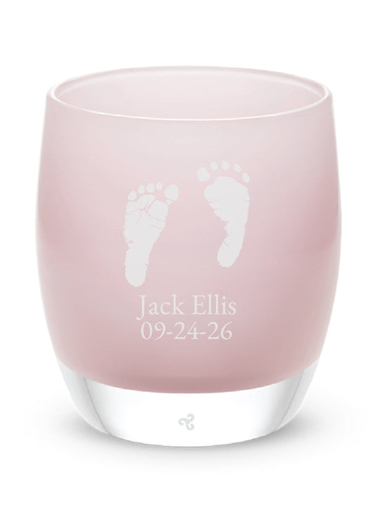 Pink glass tea light holder with white footprints and text on a white background