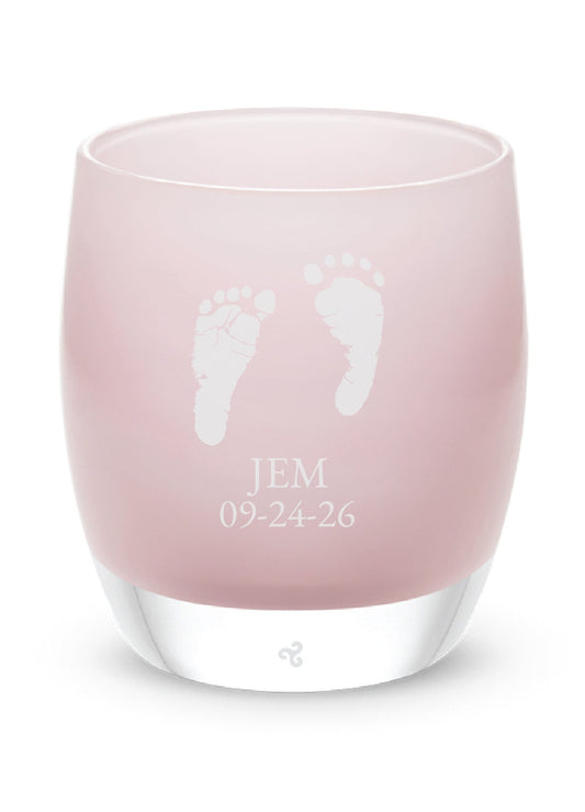 Pink glass tea light holder with baby footprints and text on a white background