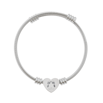 Silver cable bracelet with a heart-shaped charm featuring footprints on a white background