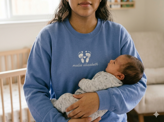 Person holding a baby wearing a footprint sweatshirt.